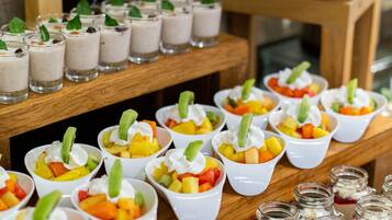 Una presentación de postres con diversas frutas y postres a base de crema en pequeños vasos y tarros.