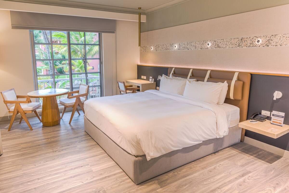 Ett modernt hotellrum med en stor säng, ett skrivbord och stolar.