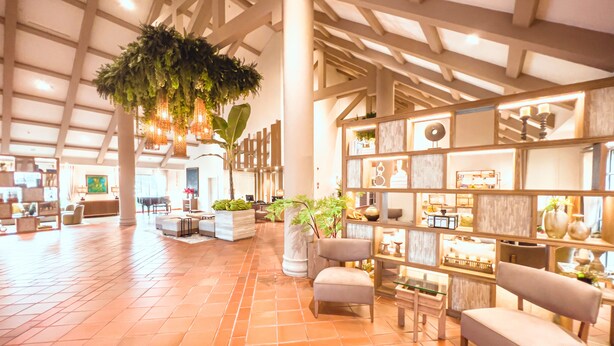 A spacious lobby with a high ceiling, large windows, and a central indoor plant. There are seating areas with cushioned chairs and a coffee table. - Oro Verde Machala (Machala)