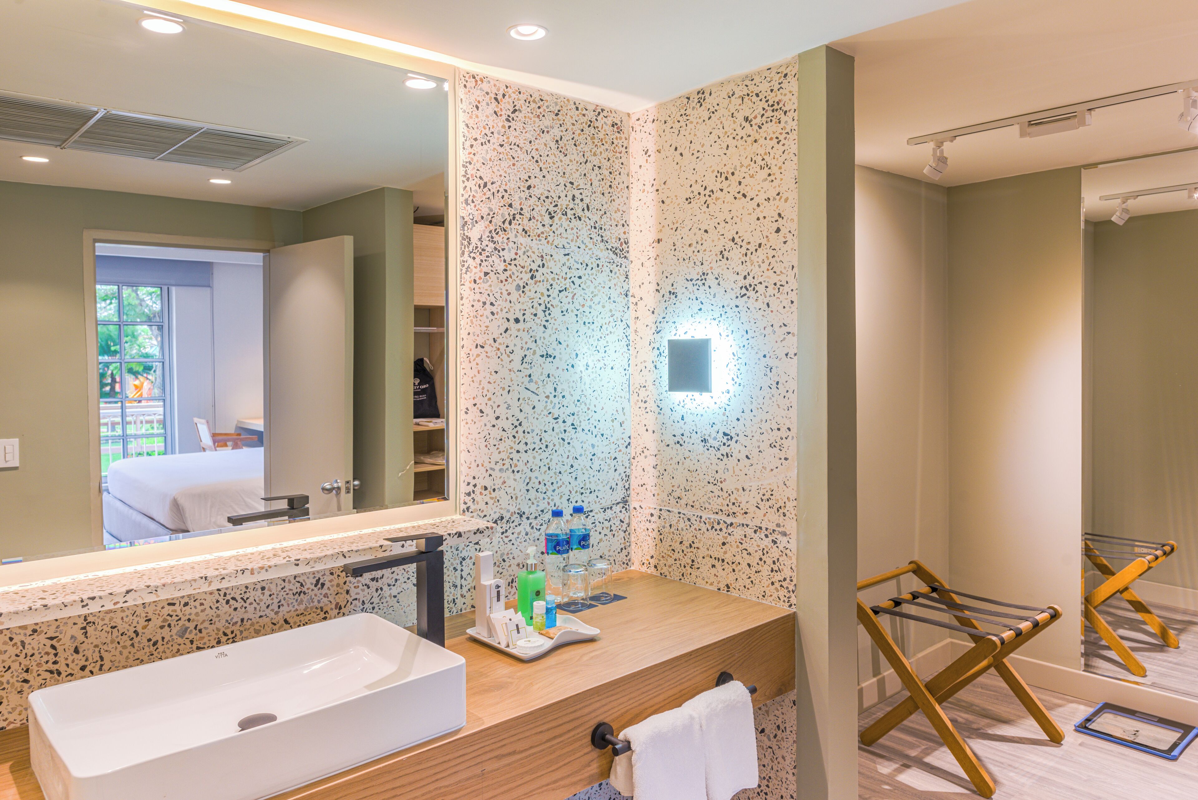 Un baño moderno con un lavamanos grande, un espejo y un perchero para toallas.