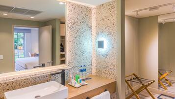 Un baño moderno con un lavamanos grande, un espejo y un perchero para toallas.