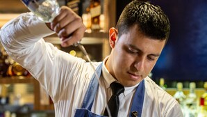 A bartender preparing a drink with a shaker and a bottle of liquor. - Oro Verde Machala (Machala)