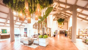 A spacious lobby with a high ceiling, large columns, and hanging plants. There are seating areas and a reception desk. - Oro Verde Machala (Machala)