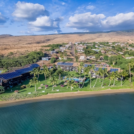 An aerial view of a coastal resort with multiple buildings, solar panels, and a beachfront.