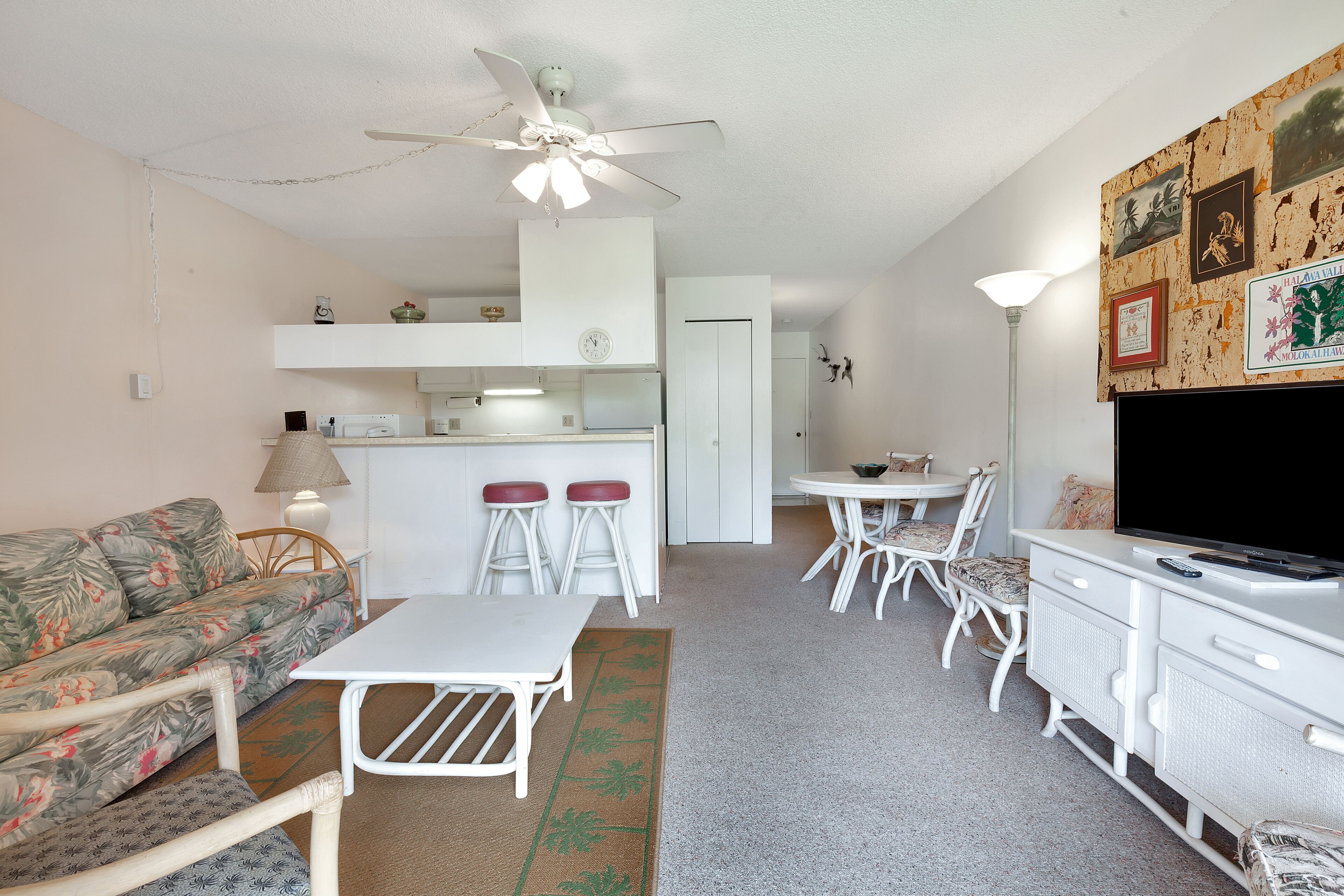 Un espacio habitable compacto con kitchenette, comedor y zona de estar con sofá y sillas.