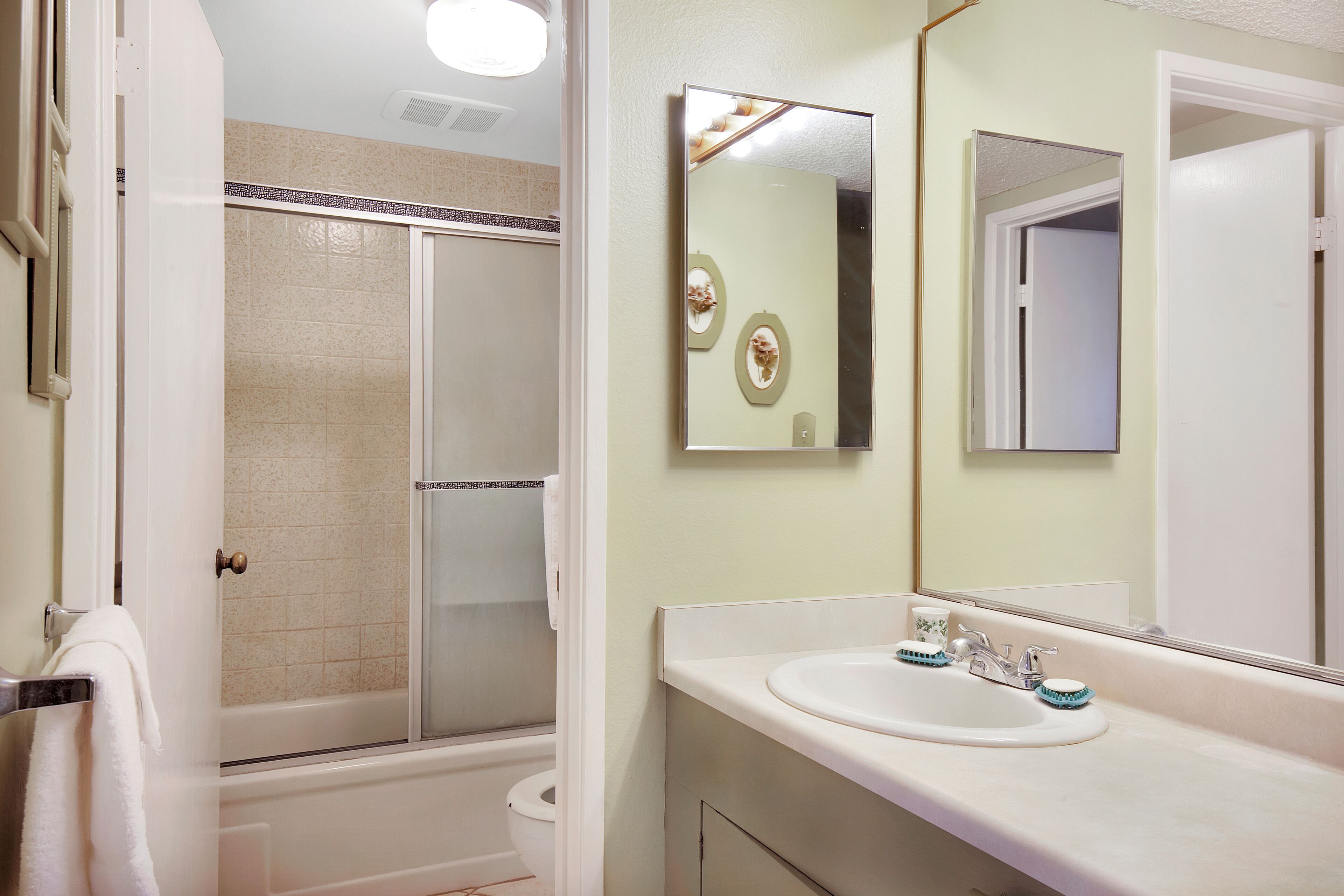 A bathroom with a shower, toilet, sink, and mirrors.