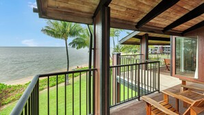 Un balcon en bois offrant une vue sur l’océan et les palmiers.
