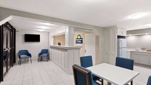 Una habitación de hotel con comedor, kitchenette y televisor montado en la pared.