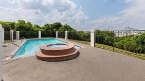 Una piscina con jacuzzi, rodeada de una cerca y follaje.