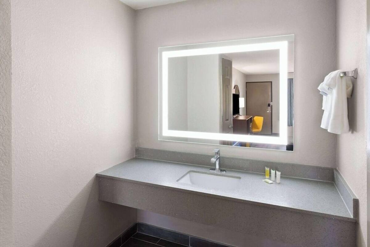 A modern bathroom with a large mirror, a sink, and a towel rack.