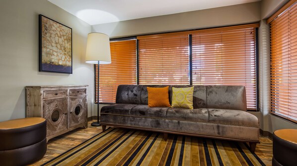A living room with a sofa, two side tables, a lamp, and a patterned rug. - Best Western Shenandoah Inn (Newnan)
