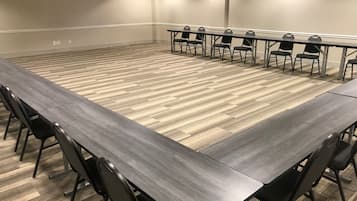 A conference room with a long table and chairs, carpeted floor, and plain walls.
