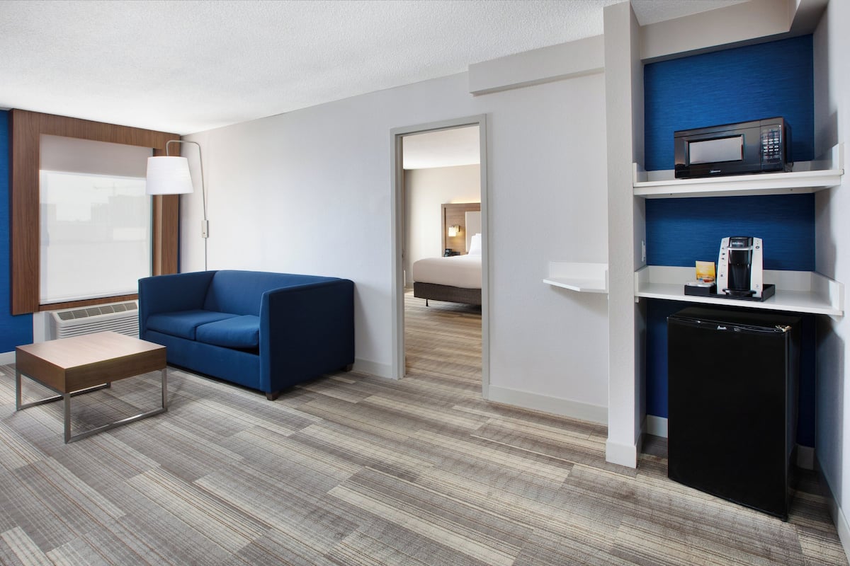 Ein Hotelzimmer mit einem blauen Sofa, einem kleinen Tisch, einer Mikrowelle und einem Kühlschrank.