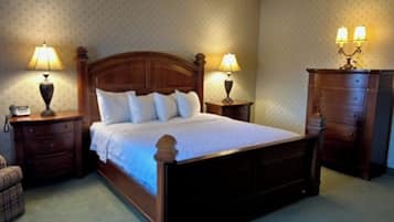 A bedroom with a wooden bed, two bedside tables with lamps, a nightstand, a dresser, and a patterned wall.