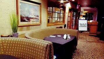 A restaurant interior with a table set for two, a large painting on the wall, and a sign for 'Steak & Anchor'.