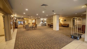 A hotel lobby with a carpeted floor, seating area, and a dining section.