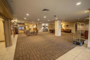 Un hall d'hôtel doté d'un sol recouvert de moquette, d'un espace salon et d'un coin repas.
