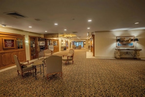 Un hall d’hôtel avec un sol recouvert de moquette, des meubles en bois, un lustre et une enseigne indiquant « Steak & Anchor Captains Cove ».