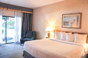 Une chambre d’hôtel avec un grand lit, une chaise, une lampe et un tableau encadré au mur.