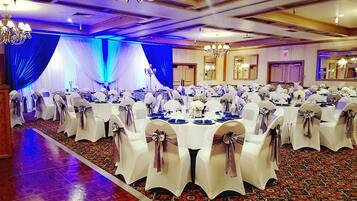 Une salle de banquet avec des tables rondes, des nappes blanches et des chaises décorées de nœuds.