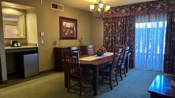 Un coin repas comprenant une table, des chaises, un lustre, un tableau et une fenêtre avec des rideaux.