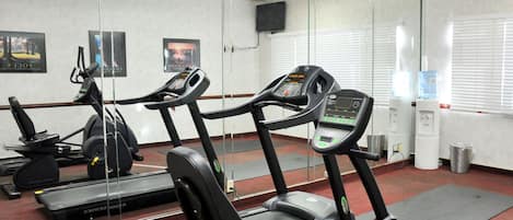 Un gimnasio con cintas de correr, máquinas de pesas y un dispensador de agua.