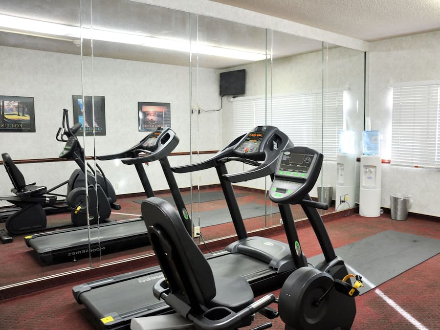 Een fitnessruimte met loopbanden, krachttrainingsapparatuur en een waterdispenser.
