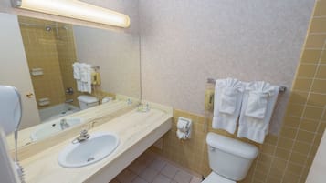Une salle de bain équipée d’un lavabo, d’un miroir, de toilettes et d’un porte-serviettes.