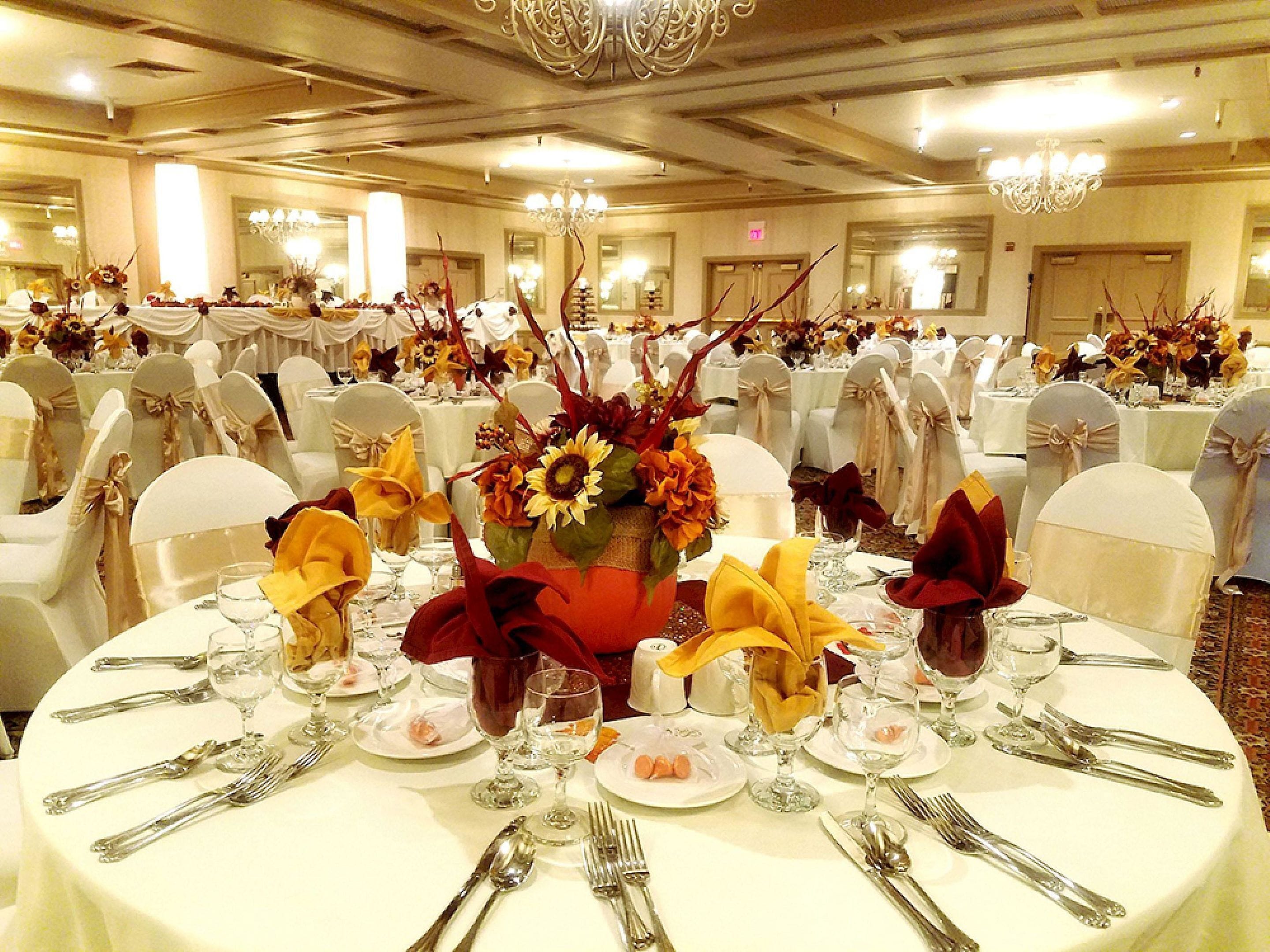 A banquet hall with round tables, white tablecloths, and floral centerpieces.