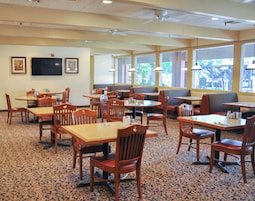A restaurant with multiple tables and booths, carpeted flooring, and large windows.
