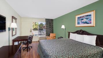 Quarto de hotel com cama, escrivaninha, cadeira e vista para o exterior.
