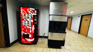 A vending machine and a water dispenser in a hallway with tiled flooring and wooden doors. - Days Inn by Wyndham North Platte (North Platte)