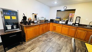 A kitchen with wooden cabinets, a coffee machine, a microwave, and a refrigerator. - Days Inn by Wyndham North Platte (North Platte)