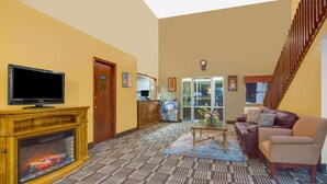 A spacious living room with a fireplace, a television, a sofa, and a staircase. - Days Inn by Wyndham North Platte (North Platte)