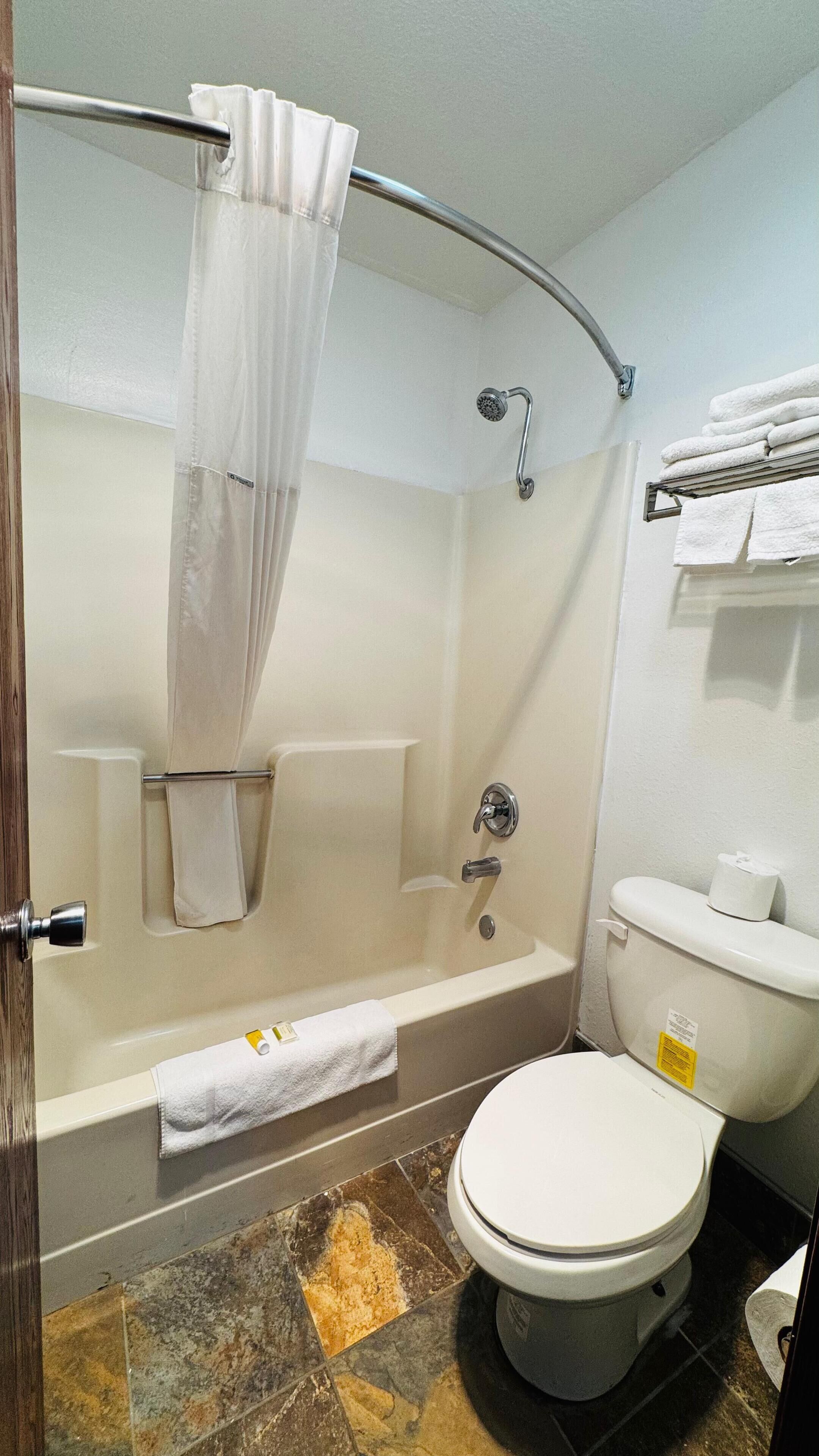 A bathroom with a bathtub, toilet, and shower curtain.