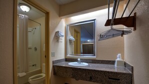 Un baño con lavabo, espejo, toallero y ducha.