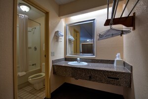 Un baño con lavabo, espejo, toallero y ducha.