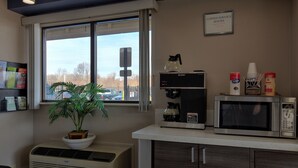 Una kitchenette equipada con cafetera, microondas y una planta en maceta.