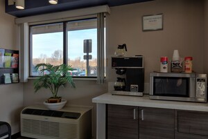 Una kitchenette equipada con cafetera, microondas y una planta en maceta.