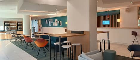 Un moderno vestíbulo de hotel con una zona de bar, espacios de estar y una recepción.