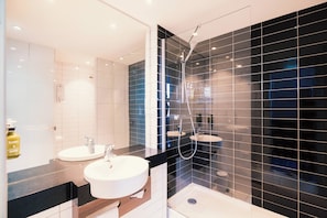 A modern bathroom with two sinks, a shower, and a large mirror.