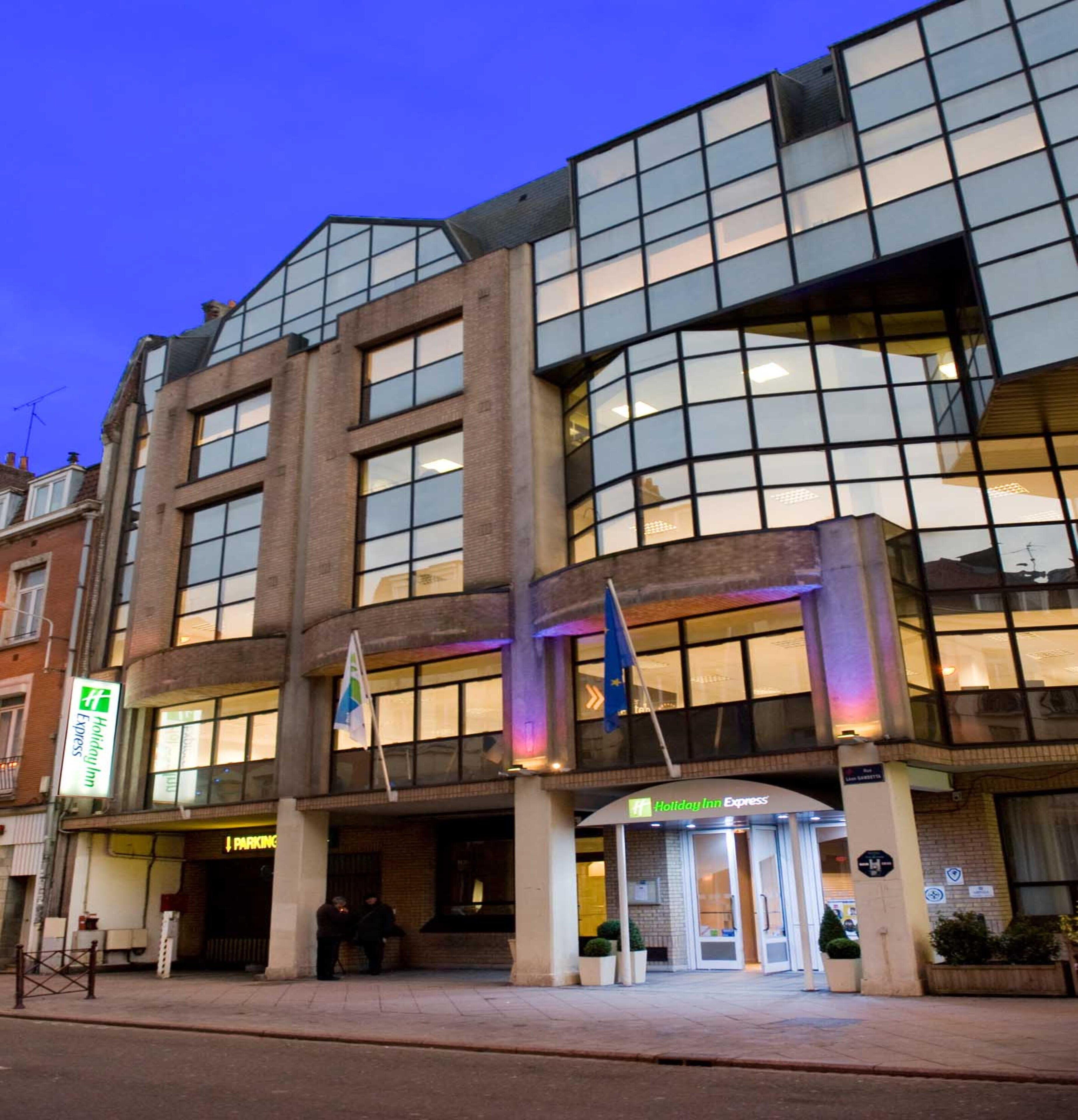 Een Holiday Inn Express hotel met een moderne glazen gevel, een duidelijke ingang en een vlag.