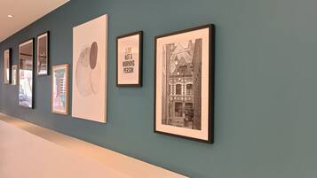 A gallery wall with various framed artworks, including a silhouette of a person and a black and white building.