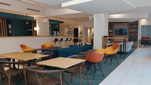 A modern restaurant with a reception area, seating arrangements, and a bar.