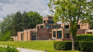 A modern building with a brick facade, large windows, and a well-maintained lawn.