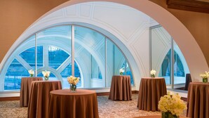 A room with large arched windows, multiple round tables with brown tablecloths, and vases with white flowers. - The Westin Pittsburgh, a Marriott Hotel (Pittsburgh)