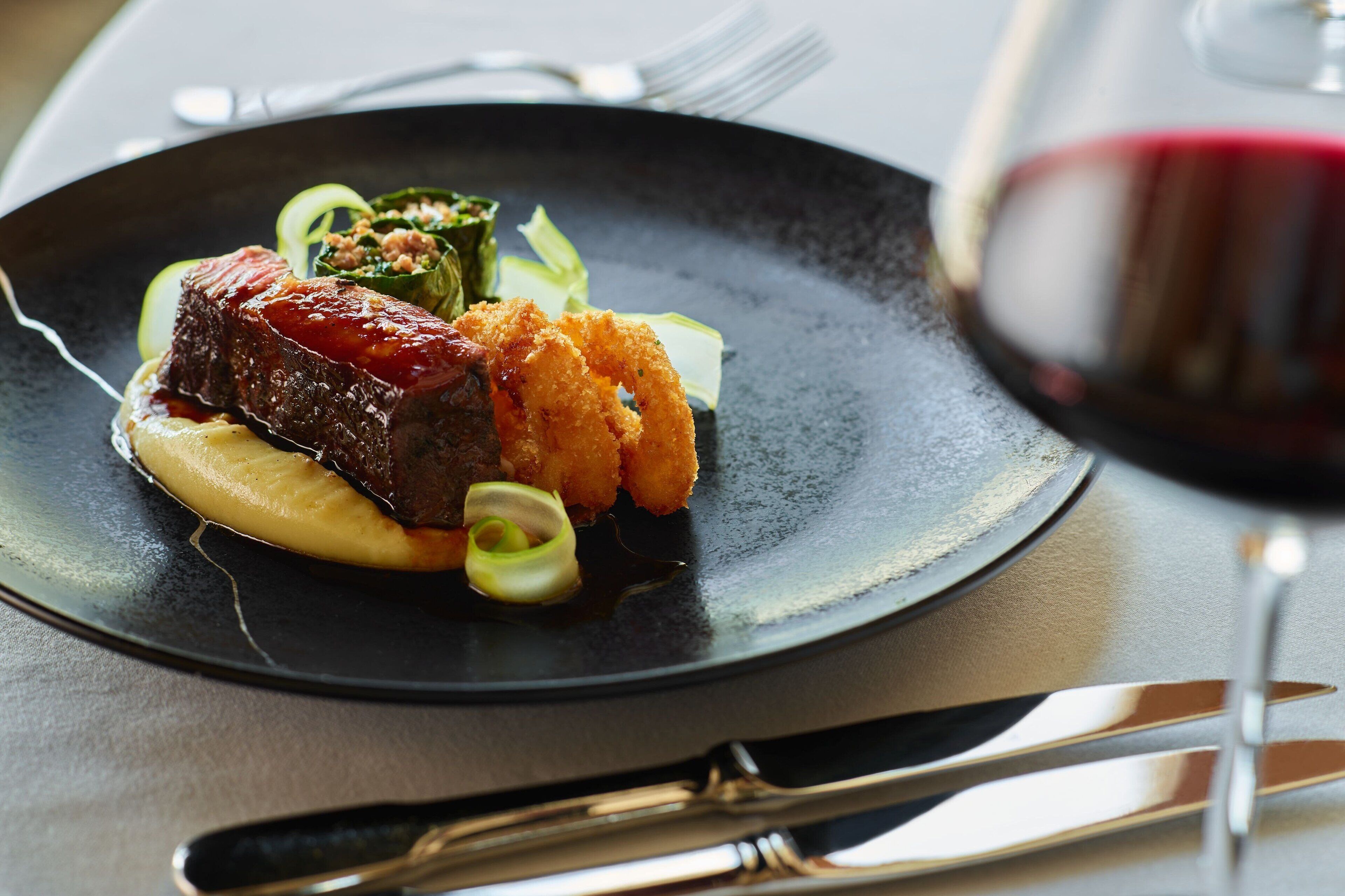A plate of food with a glass of red wine.