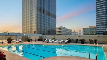 Una piscina al aire libre, sillones reclinables de piscina