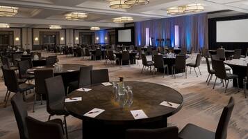 A conference room with round tables, chairs, and a large screen.