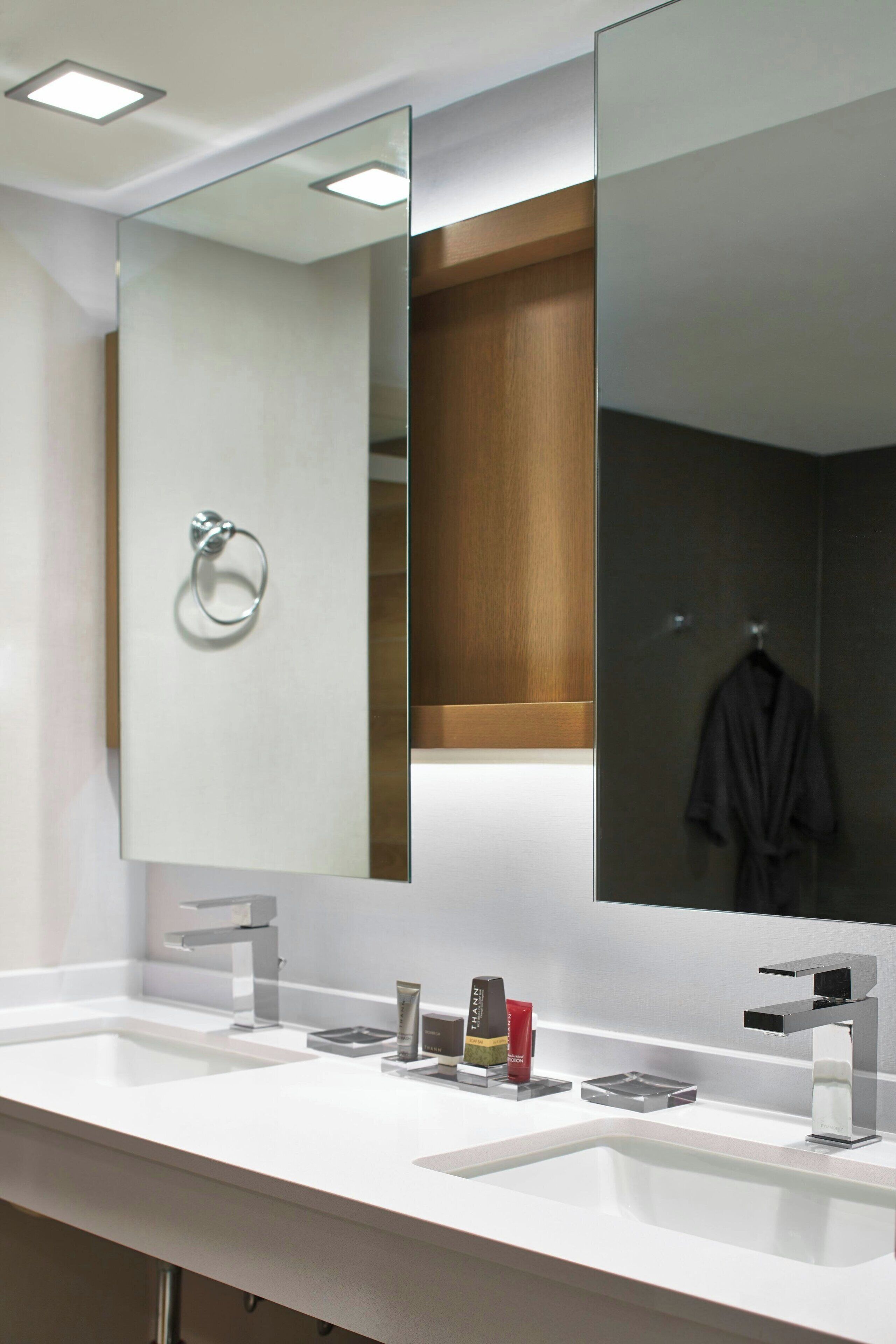 Un baño moderno con dos lavamanos, un espejo grande y un perchero para toallas.